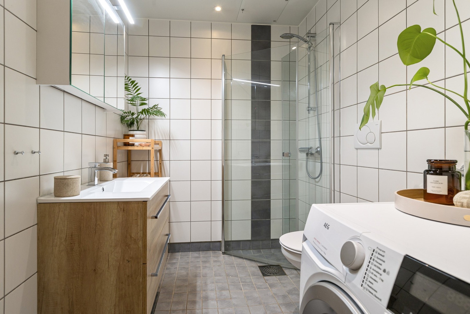 Badet er utstyrt med speilskap, heldekkende servant, vegghengt toalett og dusjhjørne med glassdører. Galleribilde