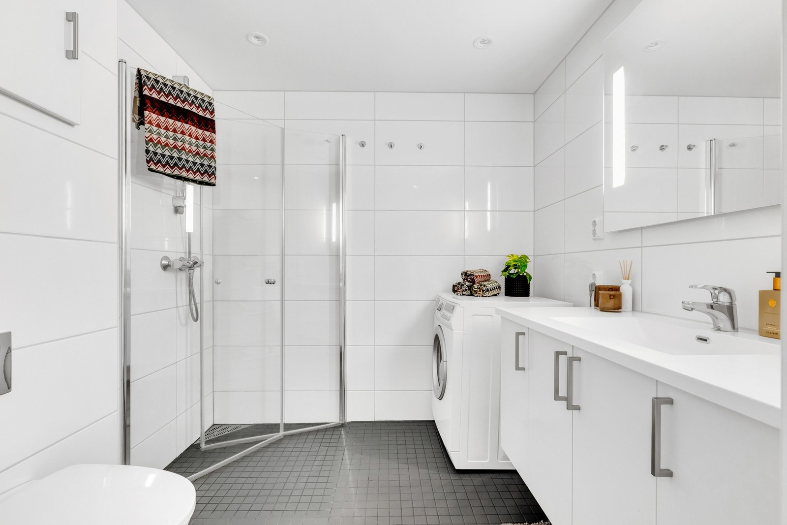 Romslig og flislagt bad med opplegg for vaskemaskin og med varmekabler i gulv. Galleribilde