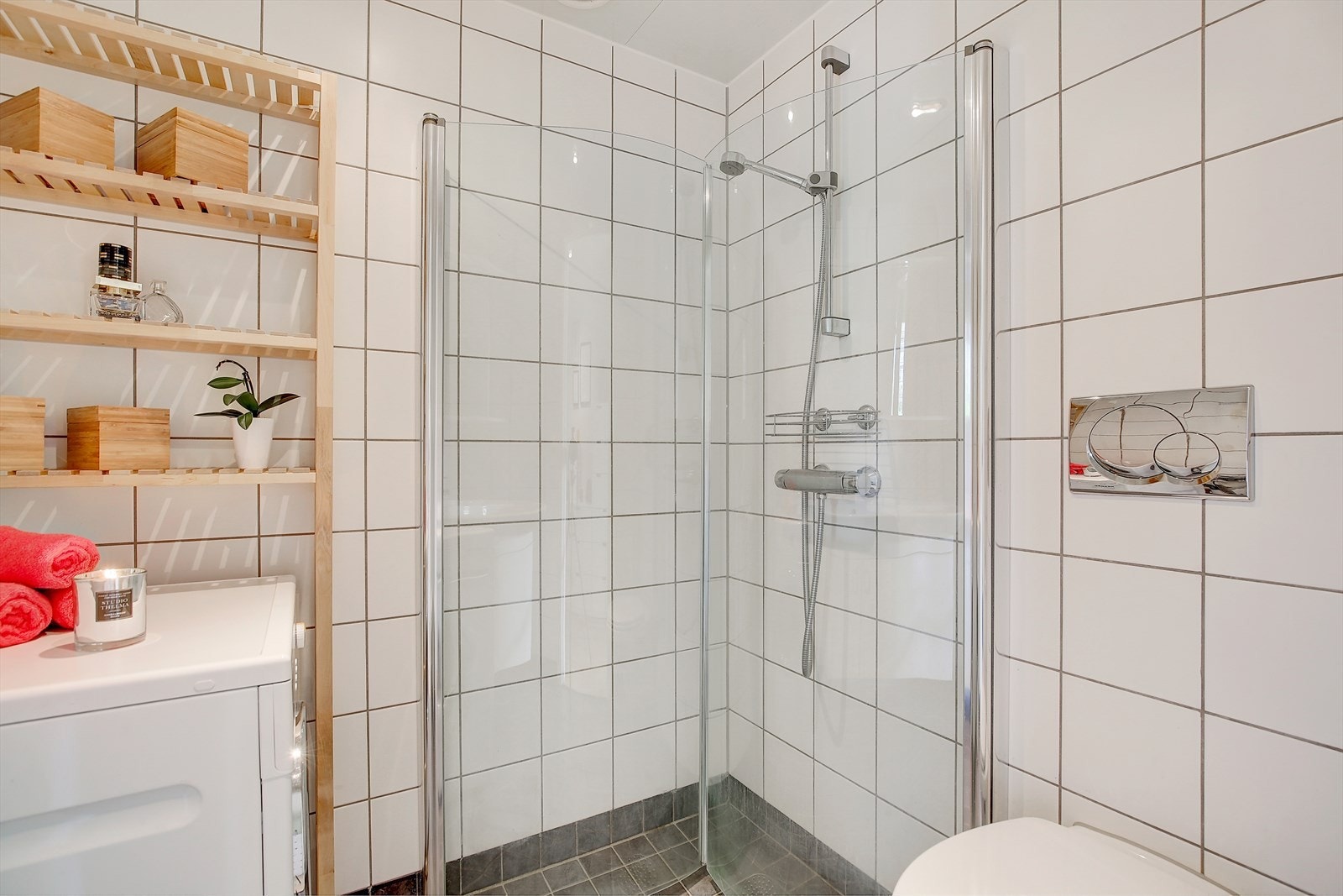 Badet er innredet med veggmonterte dusjdører, servant med underskap, speilskap med lys over, opplegg for vaskemaskin og veggmontert wc. Galleribilde