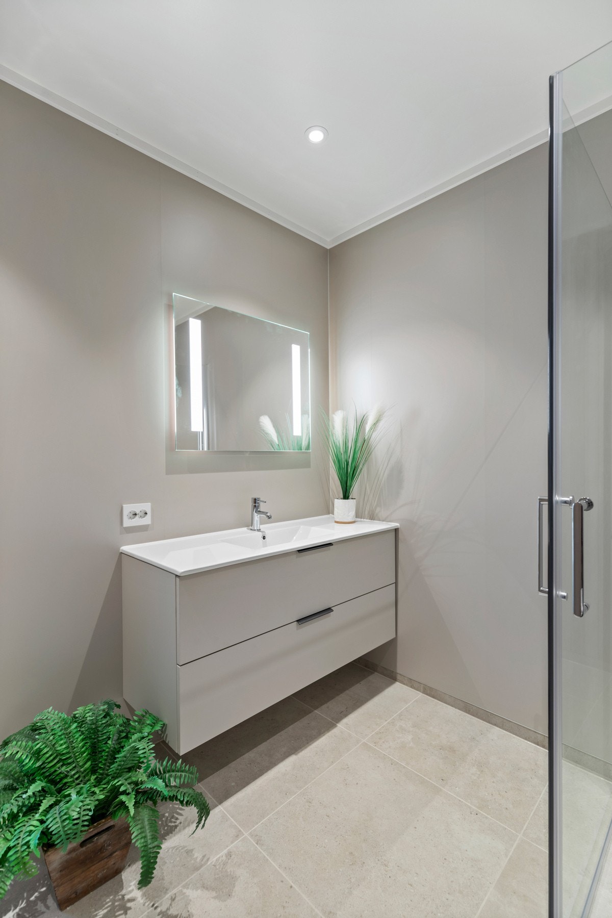 Det er montert veggholdt toalett, baderomsinnredning med helstøpt servantplate og dusjnisje med glassdører Galleribilde