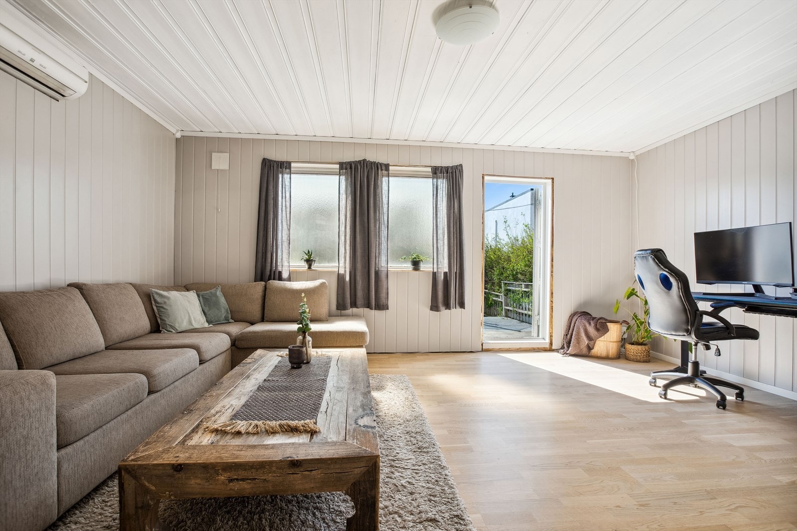 Stor stue i underetasjen med utgang til egen platting. Rommet er i dag innredet med en stor sofa og pult. Galleribilde