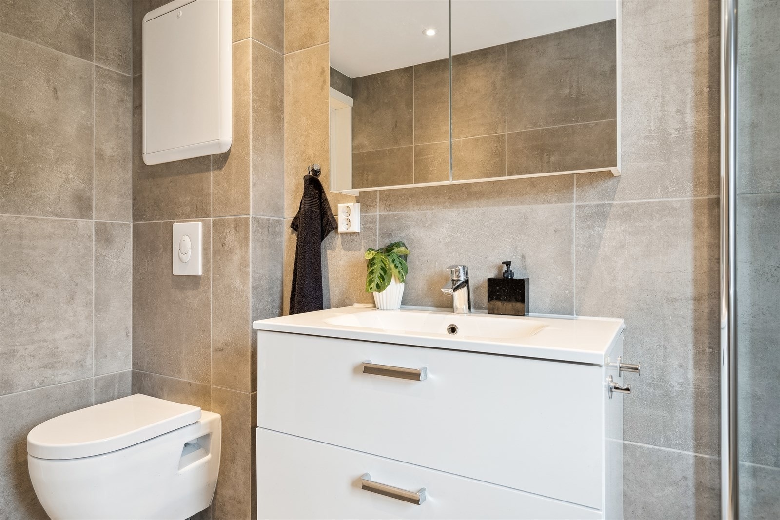 På badet er det gulvvarme, regnfallsdusj og store fliser i ulike gråtoner. Galleribilde