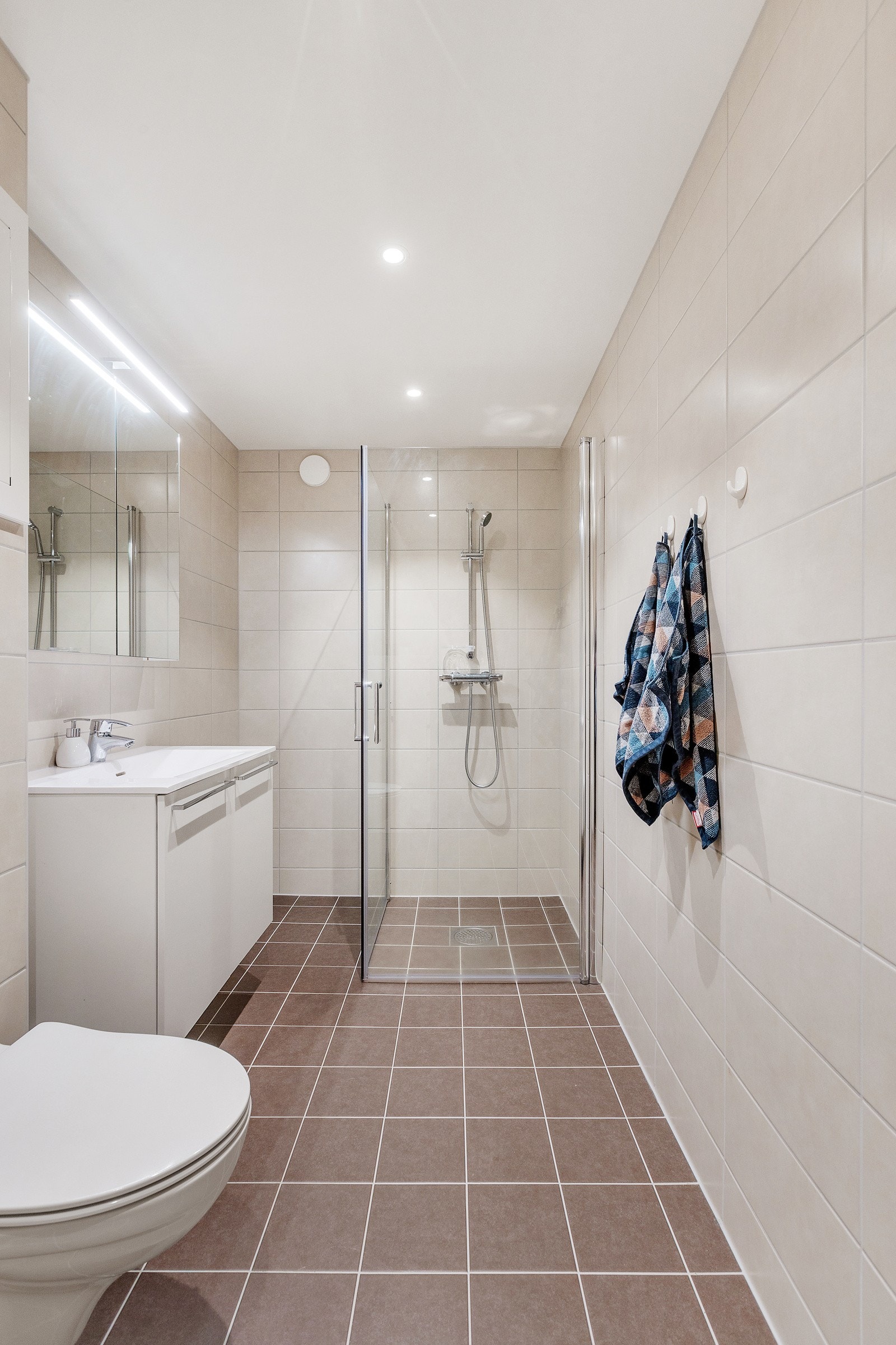 Badet har vegghengt toalett, servant med under - og speilskap og eget dusjhjørne. Galleribilde