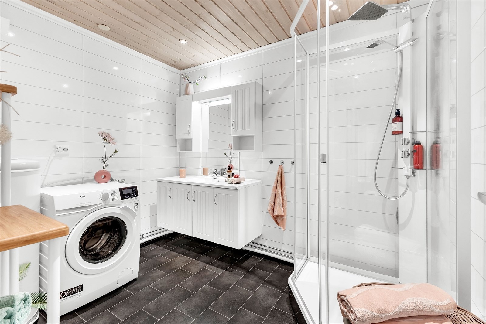 Badet er innredet med servant på innredning, dusjkabinett og opplegg for vaskemaskin/tørketrommel og varmtvannsbereder. Galleribilde