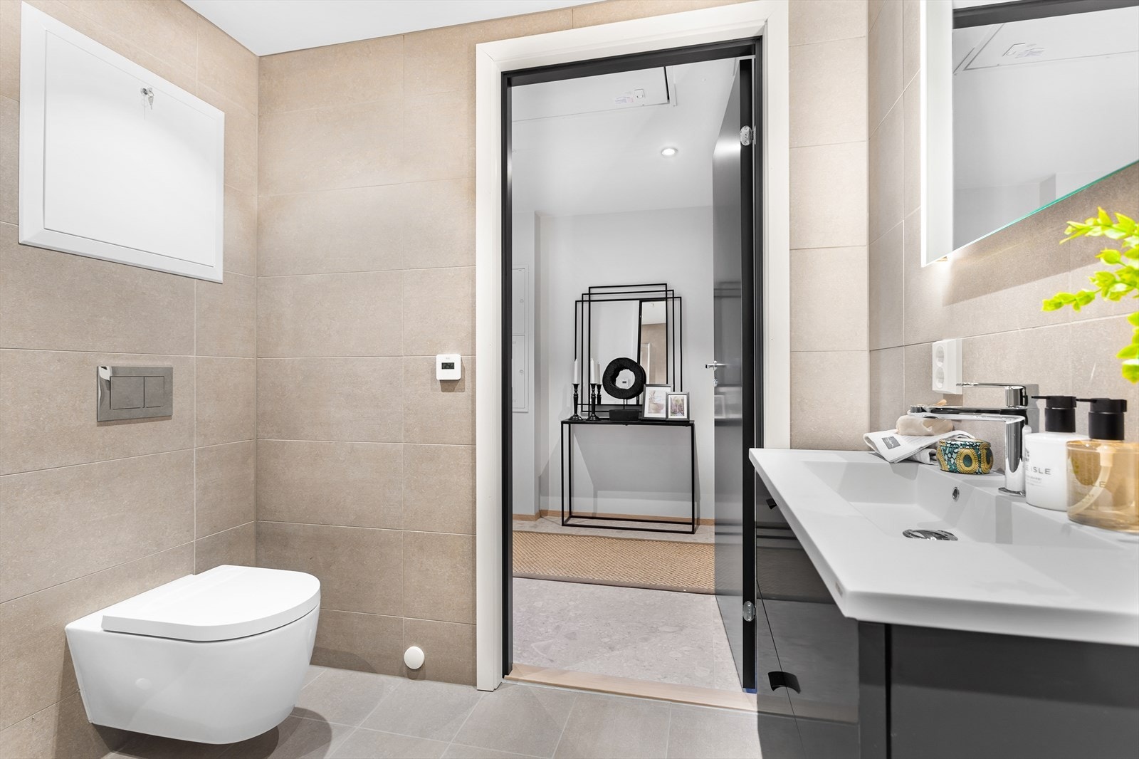 Badet er innredet med moderne servantinnredning i sorte detaljer, dusjsone og vegghengt toalett. Galleribilde