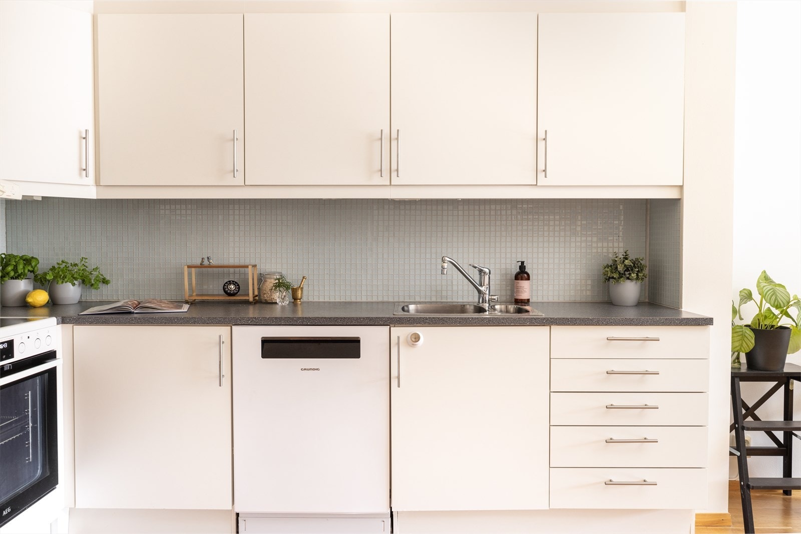 Tidløs kjøkkeninnredning med hvite glatte fronter, laminat benkeplate, 1 1/2 oppvaskkum i stål og fliser over benk. Frittstående komfyr og opplegg for oppvaskmaskin. Ny komfyr og oppvaskmaskin i 2023. Galleribilde