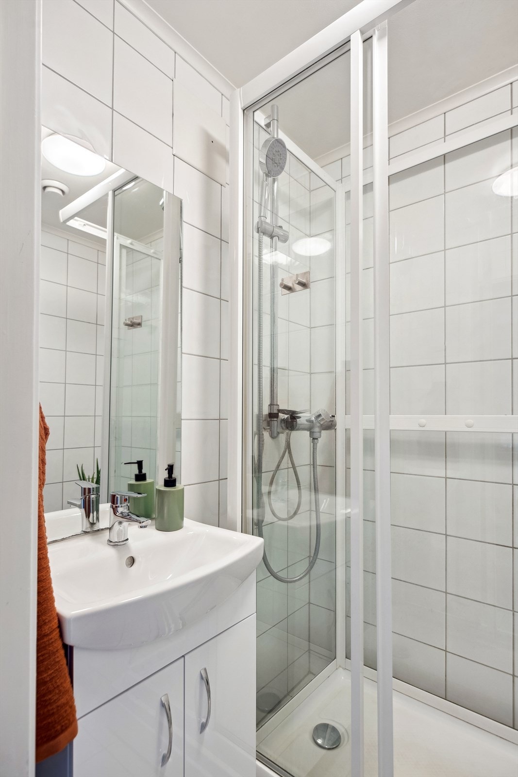 Baderommet er utstyrt med gulvvarme, dusjkabinett, servantskap og vegghengt speil. Galleribilde