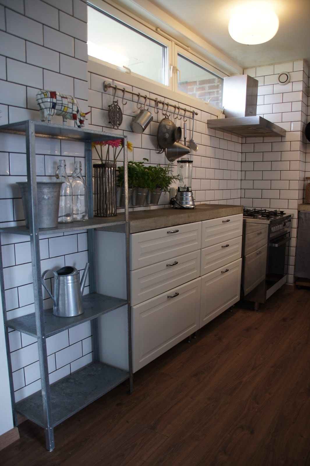 Kjøkkeninnredning med profilerte lakkerte fronter, støpt betong benkeplate, dobbel oppvaskkum, ventilator og opplegg for oppvaskmaskin. Galleribilde