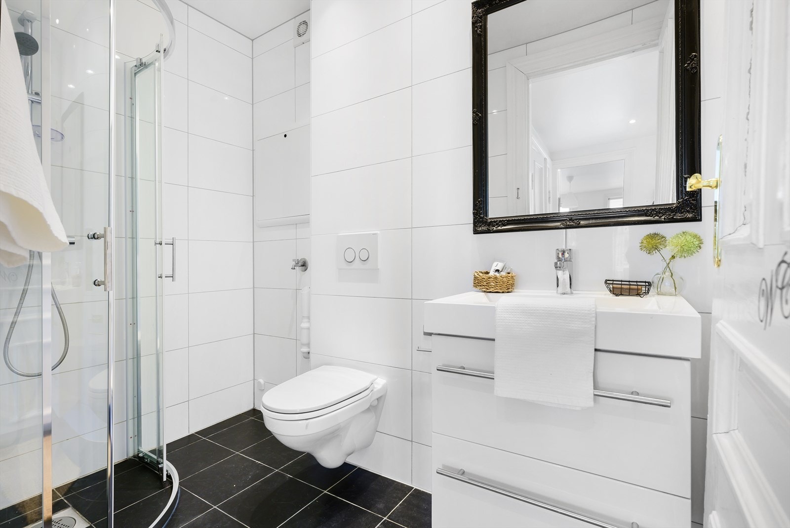 Baderom med vegghengt toalett og dusjhjørne. Opplegg for vaskemaskin. Galleribilde