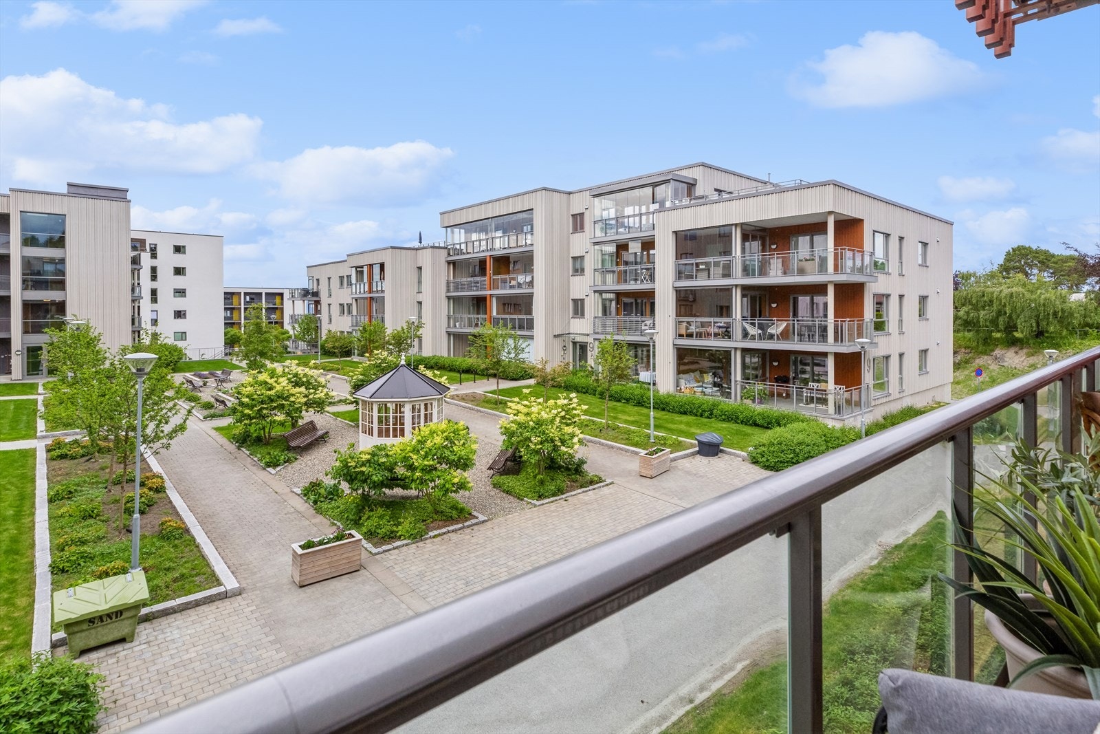 Balkongen vender ut mot et nydelig fellesareal med gangveier, sittegrupper og koselig lysthus. Galleribilde