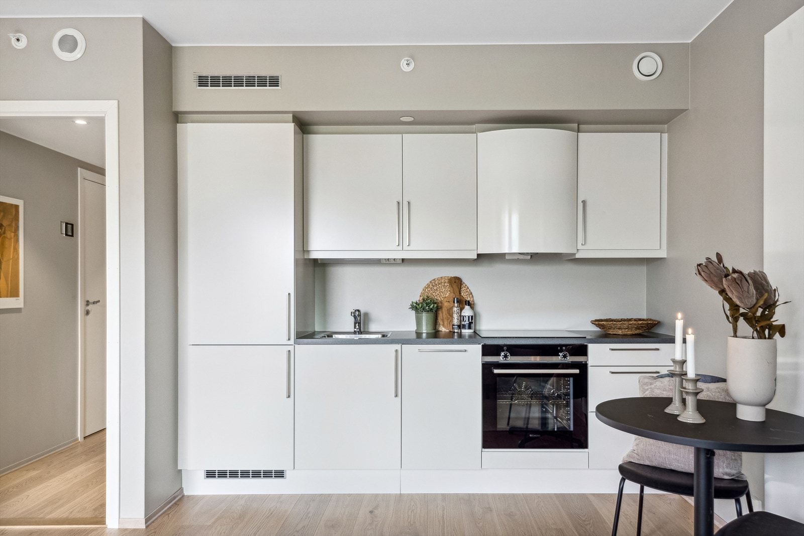 Kjøkkenet er tidløst og stilrent, utstyrt med integrert platetopp, stekeovn, oppvaskmaskin og kombinert kjøl/frys. Galleribilde