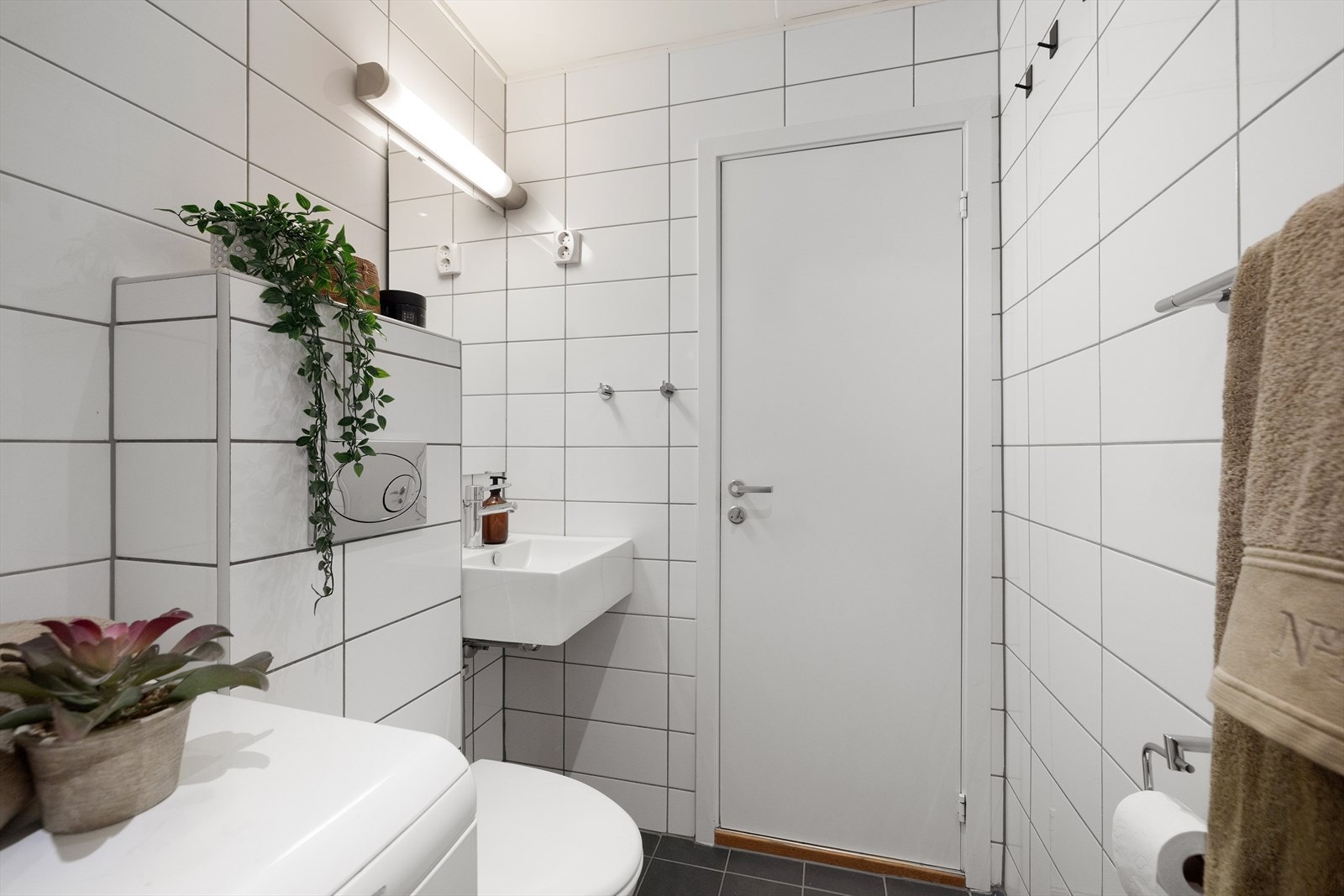 Til slutt har leiligheten et flislagt bad med servant, toalett, opplegg til vaskemaskin og dusj med glassdør Galleribilde