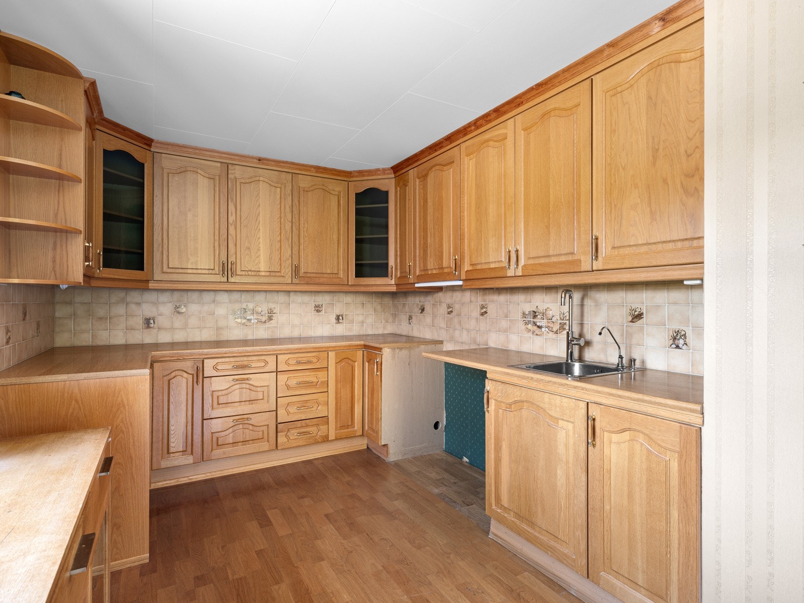 Det er ellers tilrettelagt plass for komfyr, oppvaskmaskin og frittstående kjøleskap. Over kokesonen er det ventilator. Kjøkkeninnredningen er formet i en u-form og har takhøye overskap som gir mye oppbevaringsplass. Galleribilde