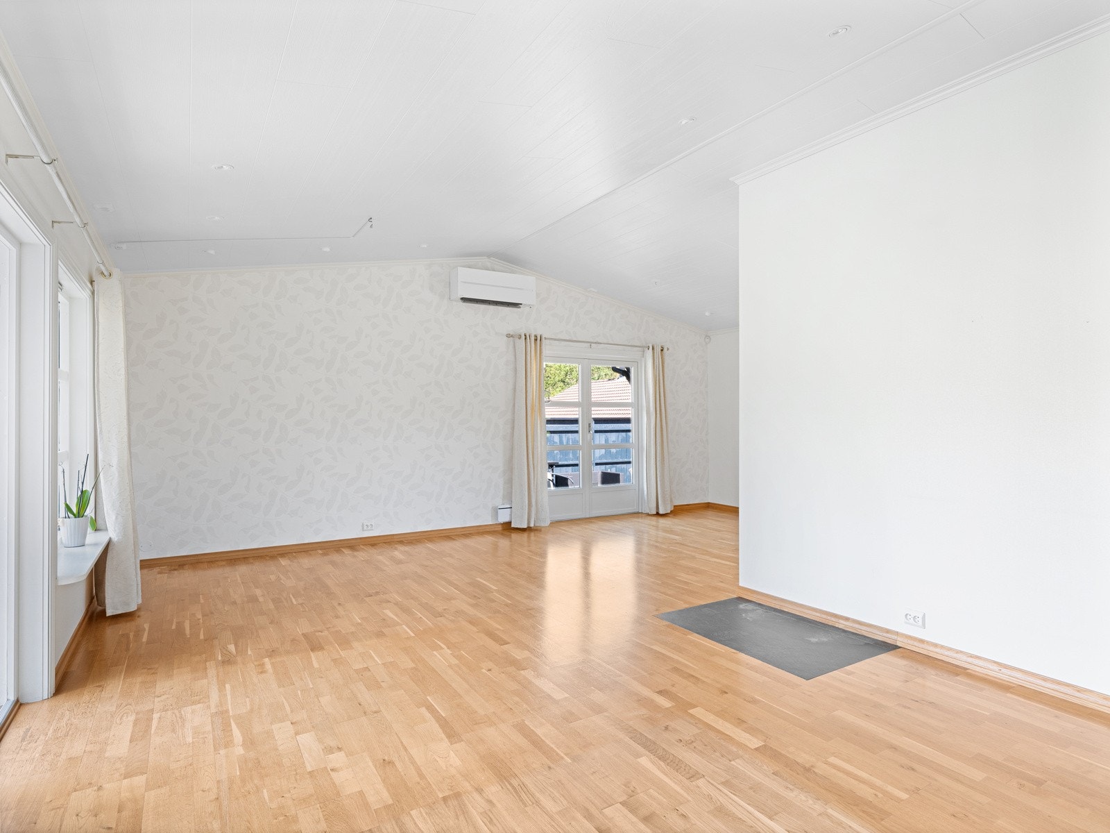 I stuen er det ekstra takhøyde, 3-stavs parkett på gulv og hvitmalte, tapetserte veggflater. Galleribilde