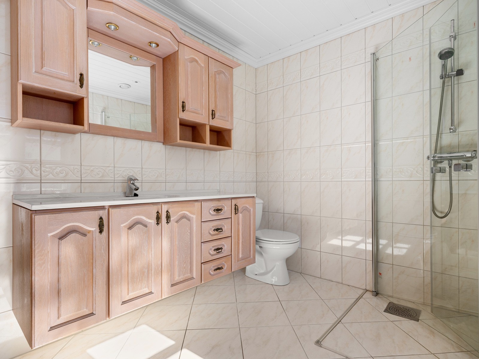 Badet ligger i første etasje og er helfliset, rommet ble oppgradert i 1997. Baderomsinnredningen består av en heldekkende servant på en skap- og skuffeseksjon med profilerte fronter, veggskap og speil med overhengende belysning. Galleribilde