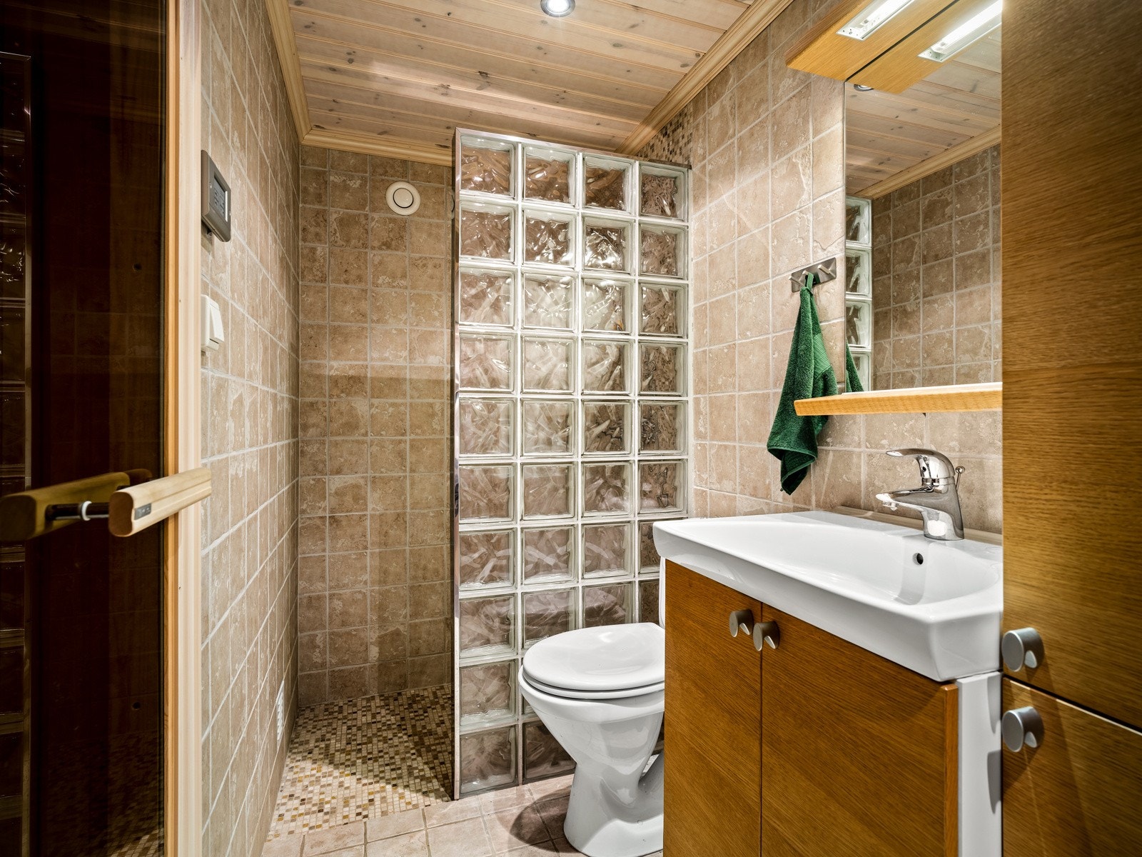 Badet i kjelleretasjen er fra 2007 og har fliser på gulvet, fliser på veggene, gulvvarme, downlights, gulvmontert toalett og en romslig dusjnisje. Innredningen består av en heldekkende servant med underskap og matchende veggskap. Galleribilde