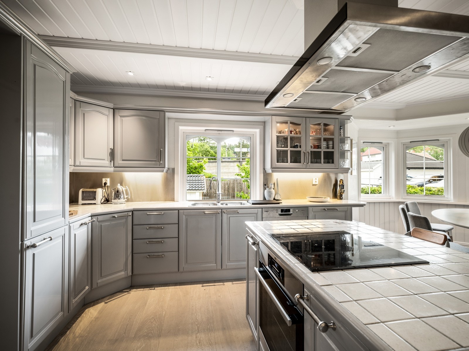 Innredningen har vitrineskap, grå, profilerte fronter og en flislagt benkeplate med dobbel, nedfelt oppvaskkum. Over deler av benken er det vindu, noe som gir litt ekstra arbeidslys på dagtid, og det er også lys i innredningen. Galleribilde