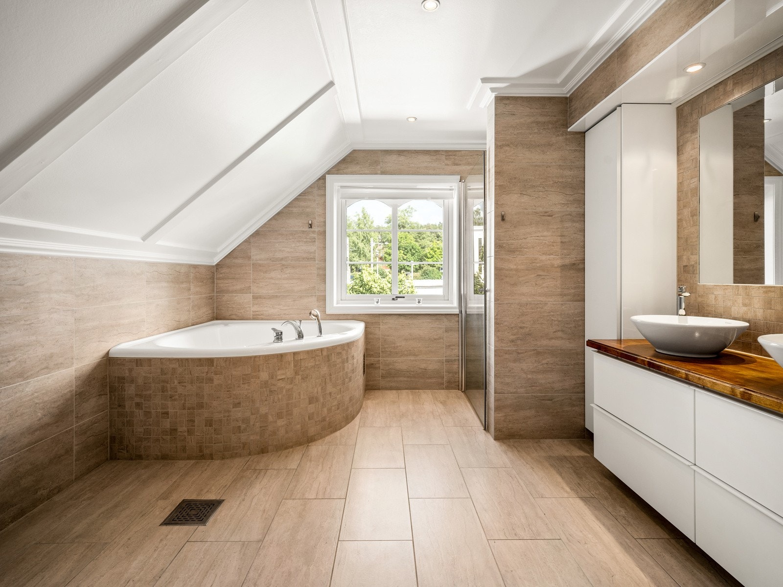 Badet i andre etasje er fra 2013 og har store, delikate fliser på gulvet og matchende fliser på veggene. I tillegg har rommet et deilig, innfliset hjørnebadekar, veggmontert toalett og en romslig dusjnisje. Galleribilde