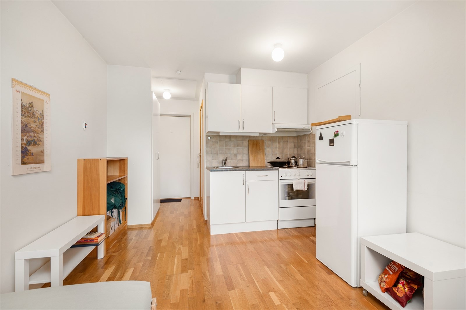 Hybelens allrom på 13,5 m² har parkett på gulv og malte overflater. Her finnes det også et lite kjøkken med muligheter for matlaging. Kjøkkenet er innredet med mekanisk avtrekksvifte over stekesonen. Galleribilde