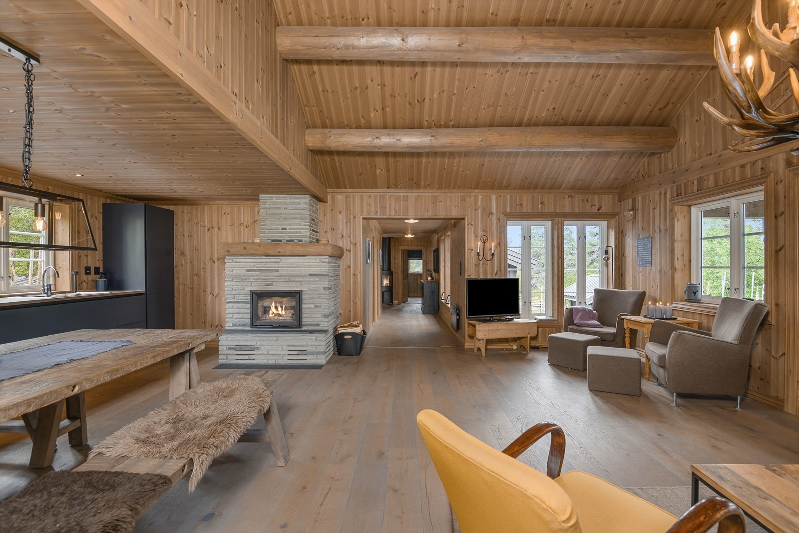 Deler av oppholdsrommet har åstak med synlige stokker. Nedsenket himling over kjøkkenet. Galleribilde