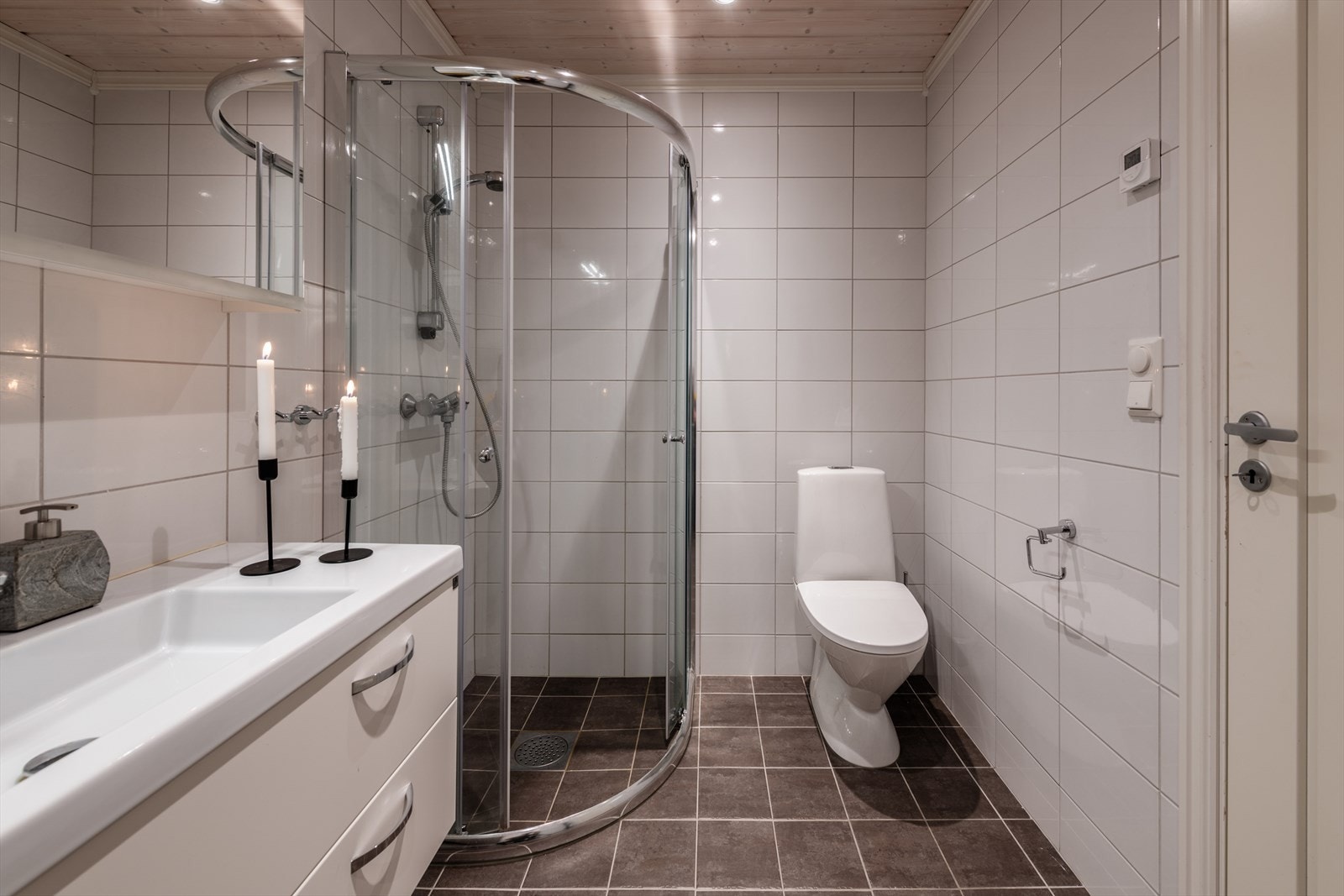 Innredet med speil, servantinnredning med håndvask, toalett og dusj med skyvedører Galleribilde