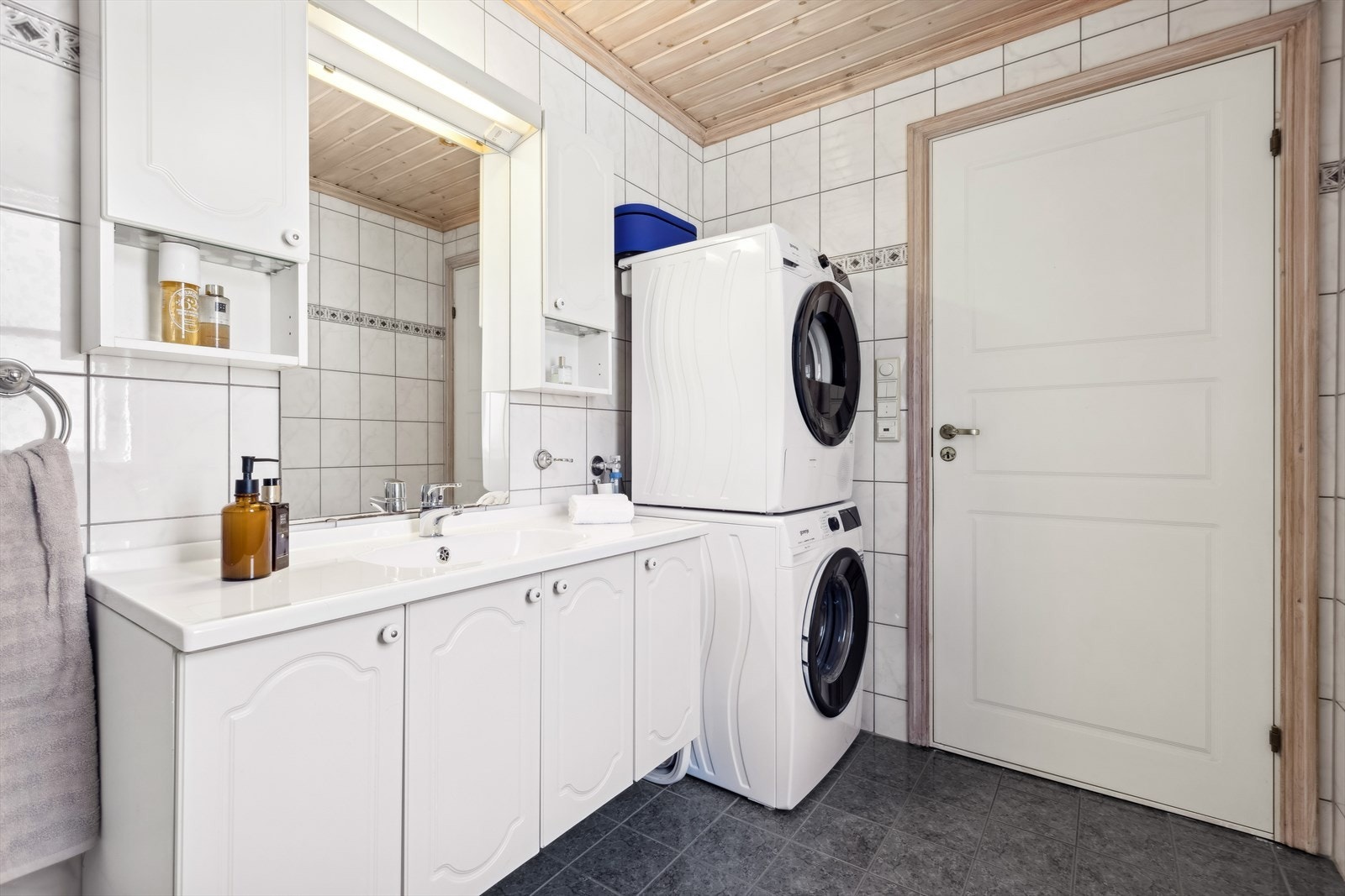 Bad beliggende i boligens første etasje er med fliselagte overflater på vegger og gulv, og med innfelte downlights i himling. Det er varmekabler i gulvet og opplegg for vaskemaskin her. Galleribilde