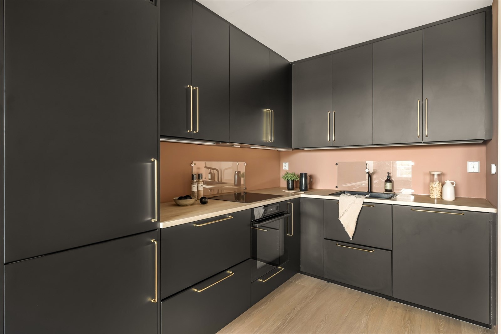 Kjøkkenet er i en moderne matt sort utførelse, med integrerte hvitevarer og detaljer i gull. Galleribilde