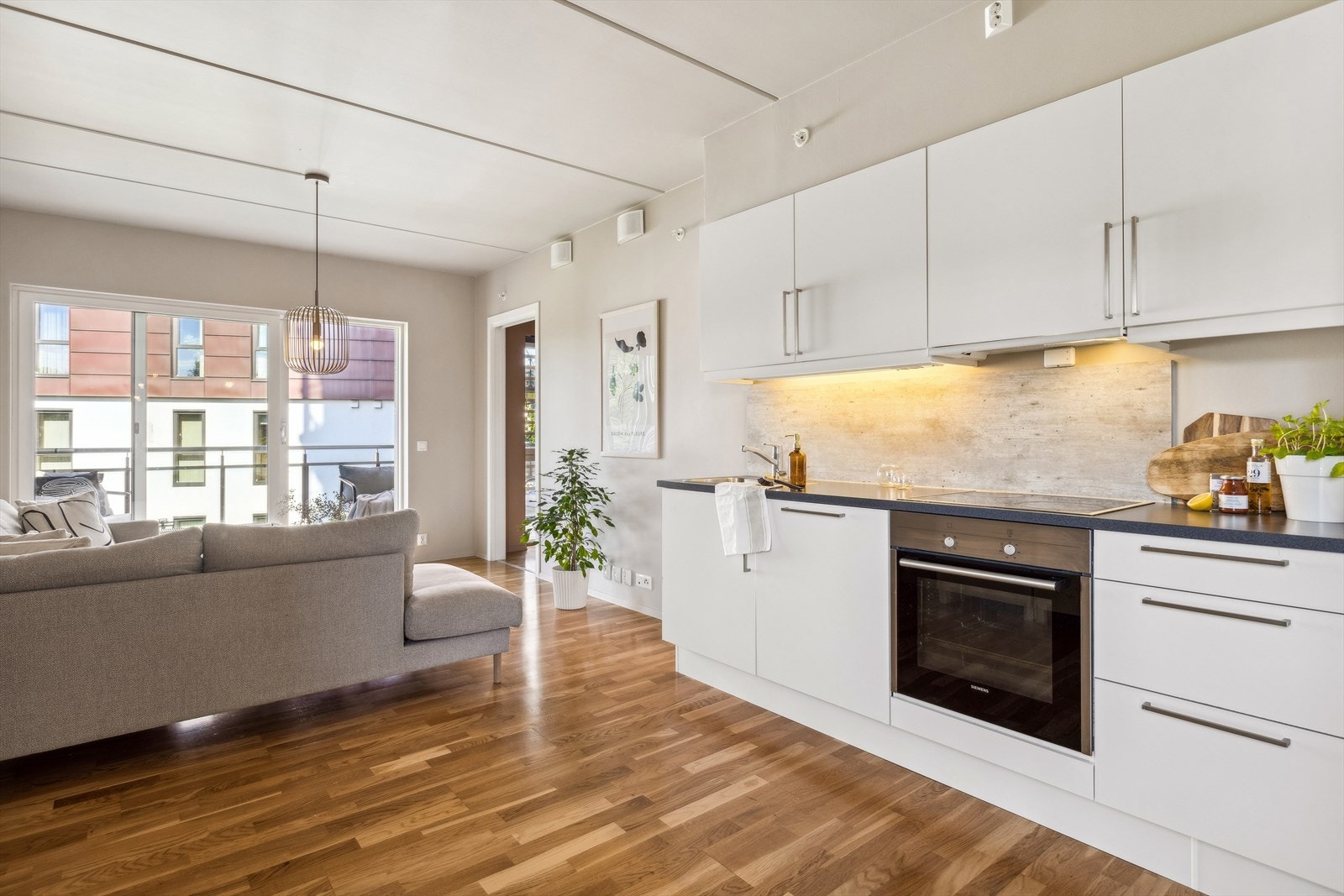 Velutstyrt og pent kjøkken med over- og underskap med folierte fronter og skrog. Laminat benkeplate med nedsenket oppvaskkum og platetopp. Galleribilde