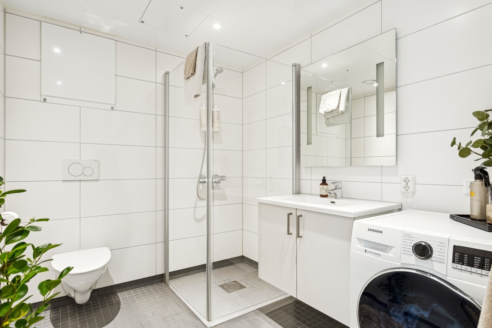 Innbydende helfliset bad med varme i gulv. Rommet har servant, servantskap, veggmontert wc, opplegg for vaskemaskin, innfellbare dusjdører, mekanisk avtrekk og rørfordelingsskap. Downlights. Et godt sted å starte dagen! Galleribilde