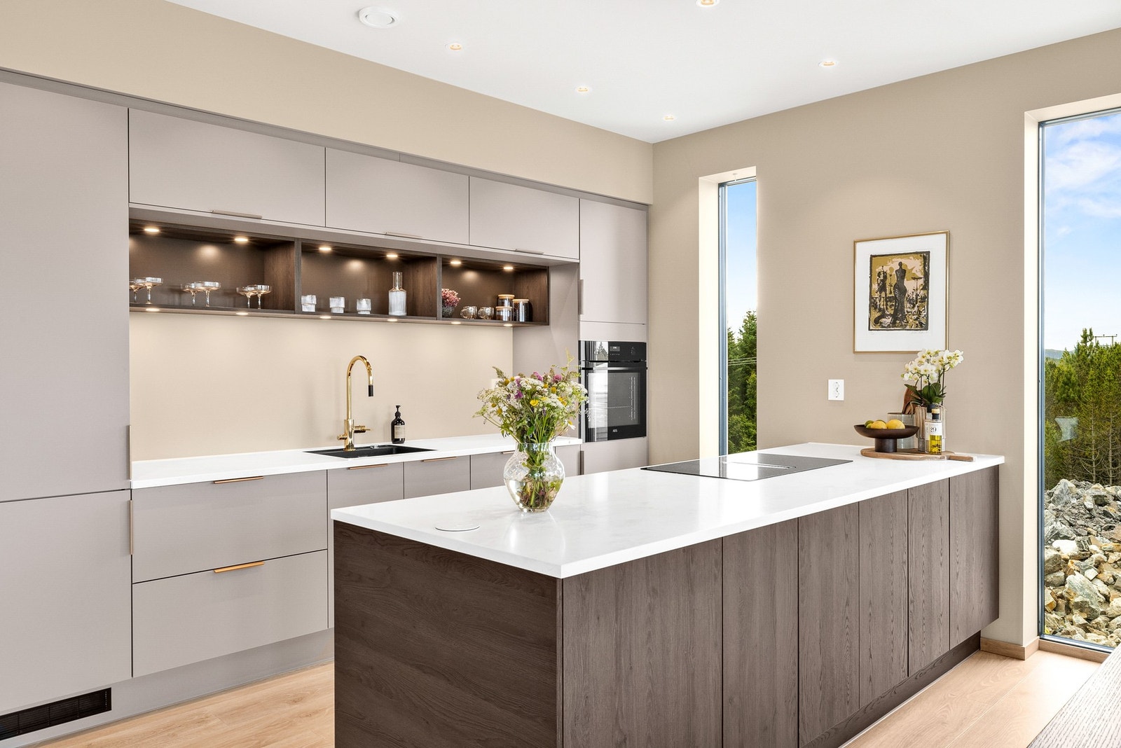 Integrert kjøl/fryseskap, oppvaskmaskin, komfyr og platetopp på kjøkkenøy med innebygd avtrekksvifte Galleribilde