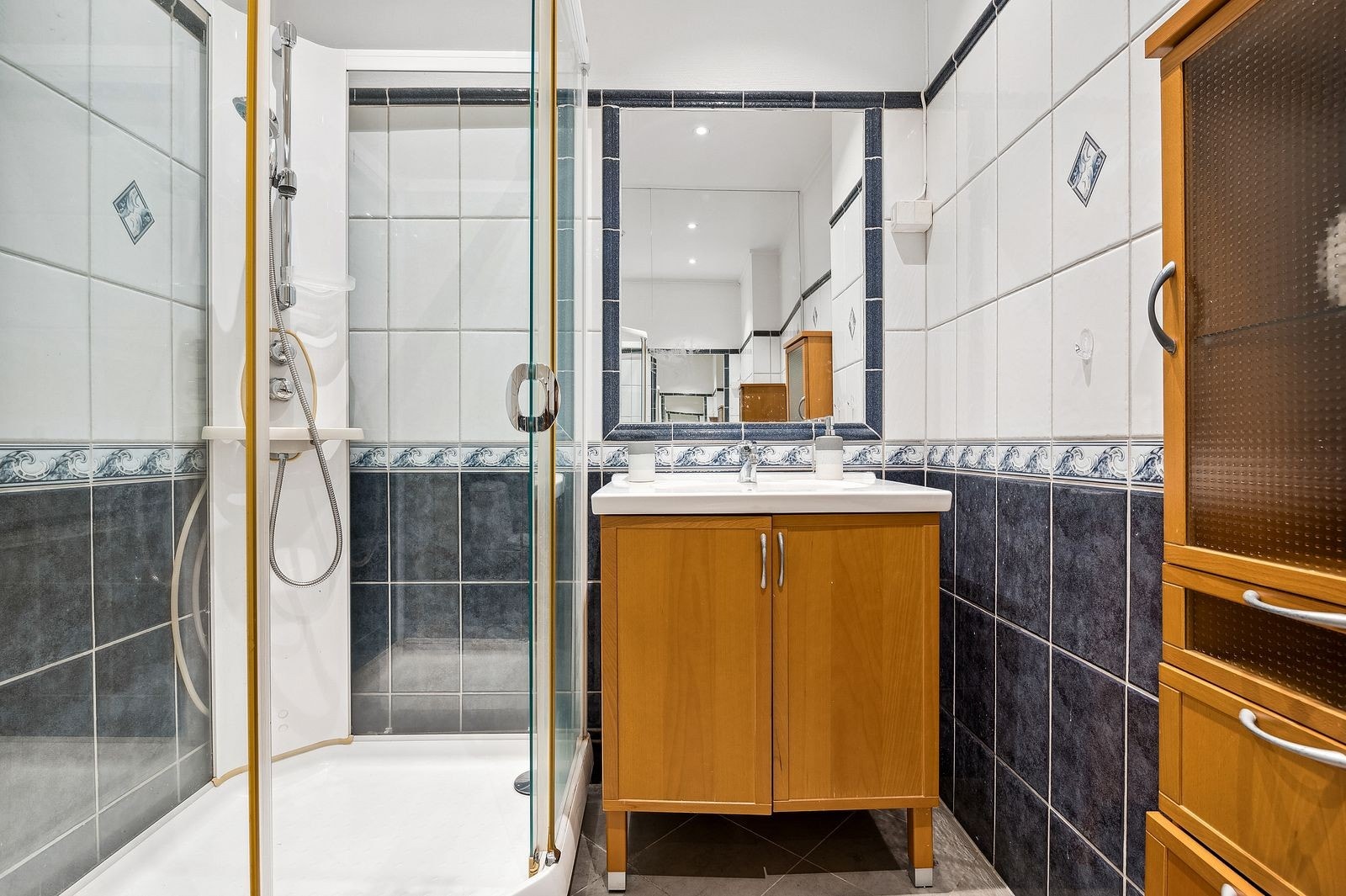 Badet er innredet med dusjkabinett, servant på innredning og toalett Galleribilde