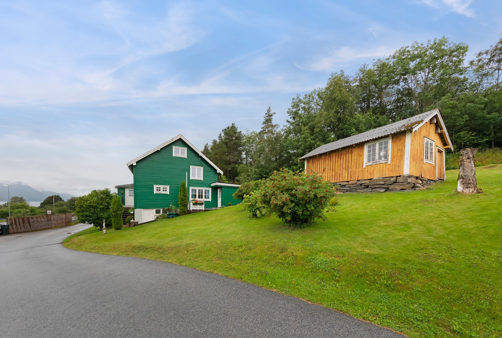 Tomten er på hele 1 494 kvm og har pent opparbeidet plen med prydbusker. To robotklippere medfølger i handelen. Galleribilde