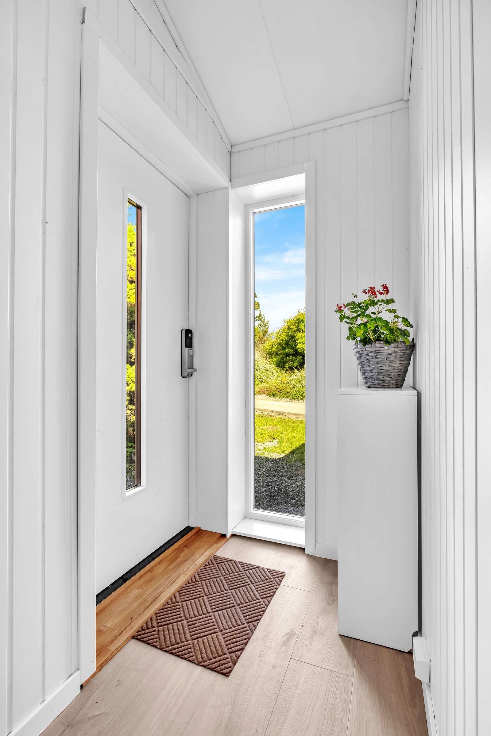 Den lyse entreen ønsker deg velkommen med hvitmalte flater og et stilrent laminatgulv. Galleribilde