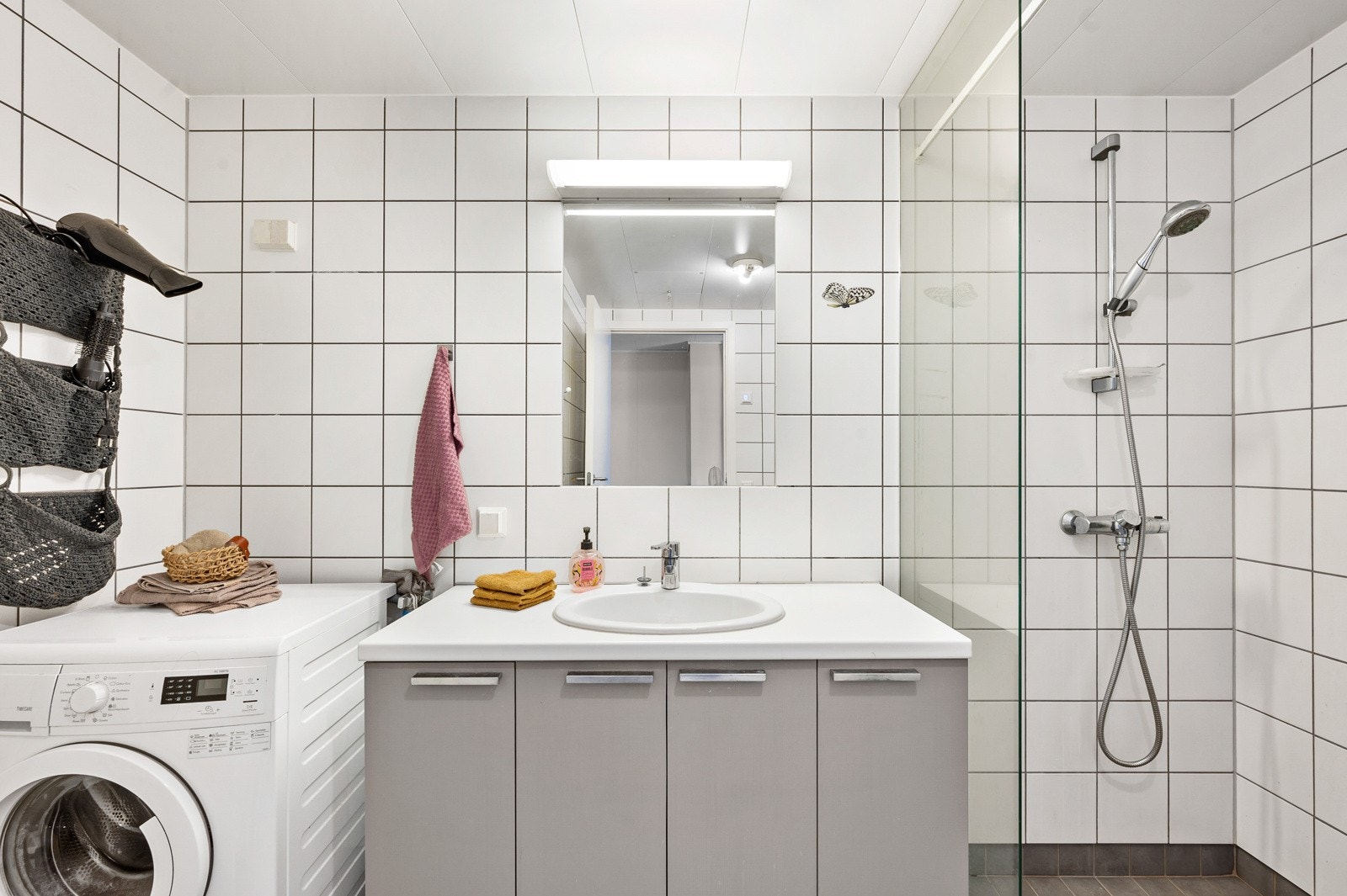 Dusjnisje med glassvegg, glassdør, to-greps armatur og vegghengt toalett. Badet har også opplegg til vaskemaskin. Galleribilde