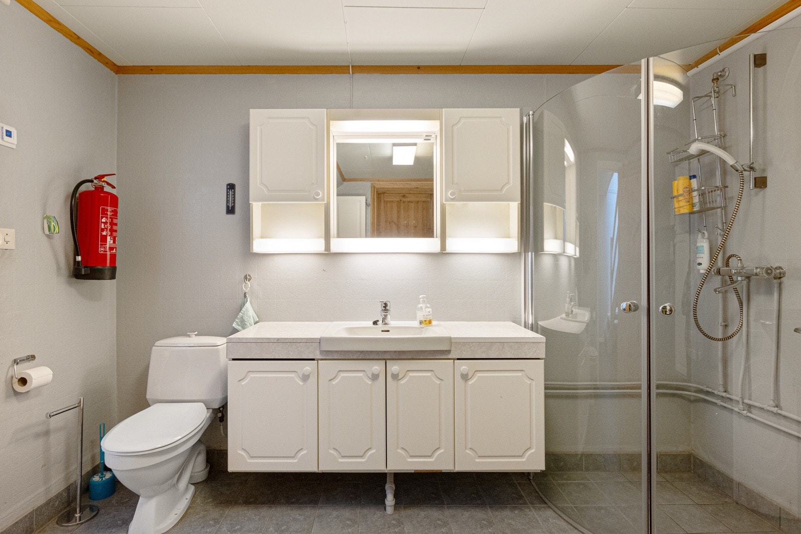 Rommet er utstyrt baderomsinnredning, dusjvegger, utslagsvask og gulvmontert wc. Det er også opplegg for vaskemaskin i rommet. Galleribilde
