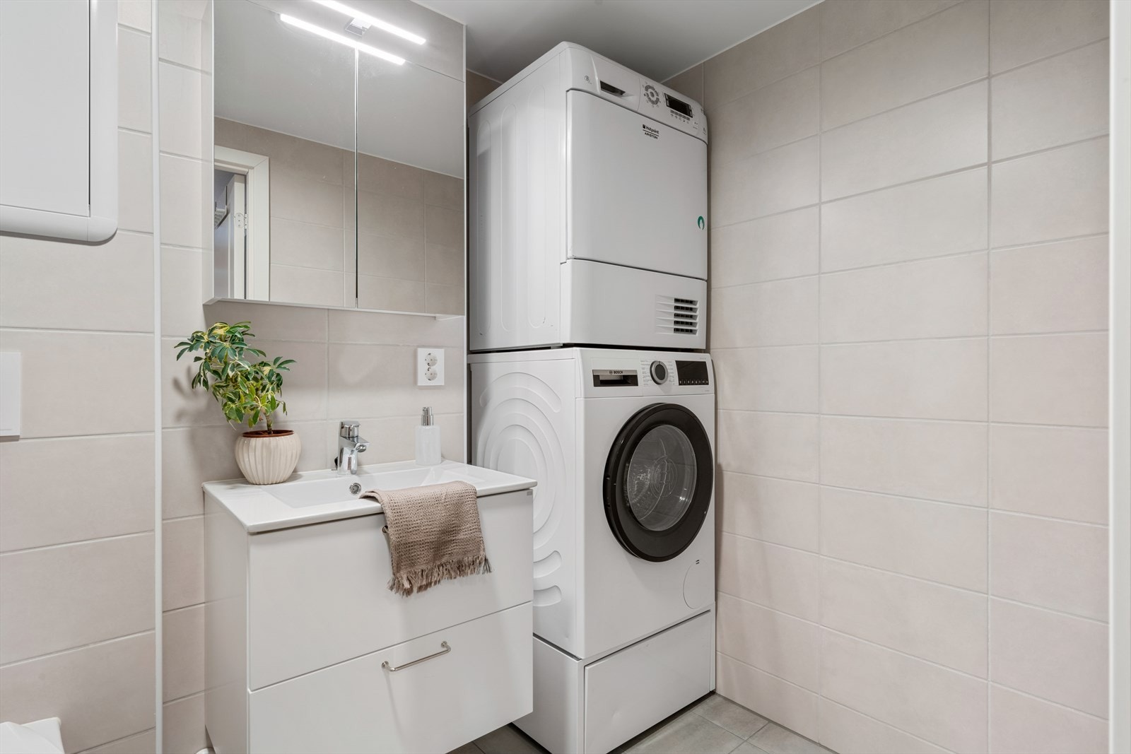 - Badet er innredet med delikate beige vegger og moderne lysegrått gulv. Merk plass til både vaskemaskin og tørketrommel - Galleribilde