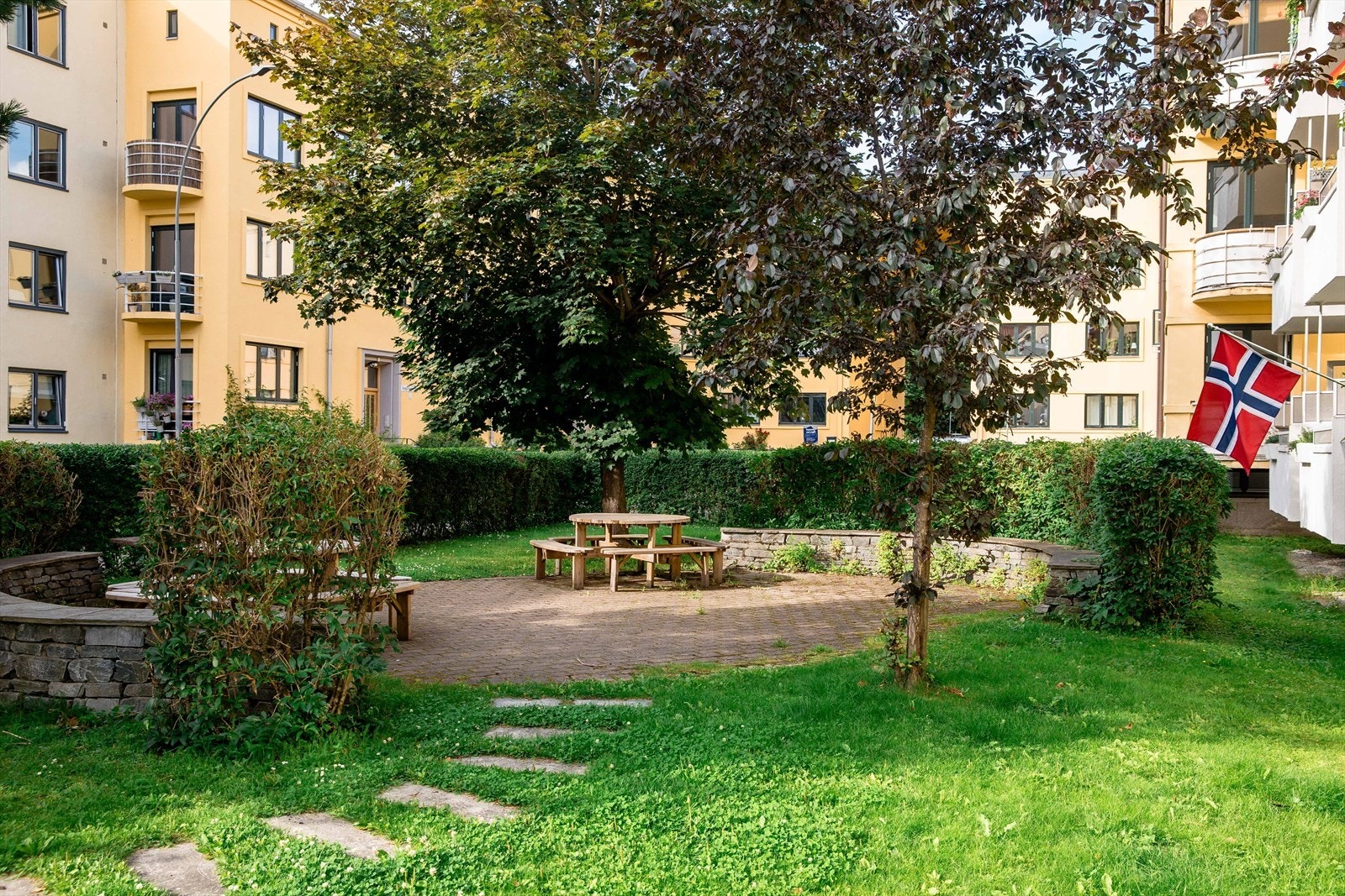 Idyllisk bakgård med flere sittegrupper, hyggelige internveier og grill. Galleribilde