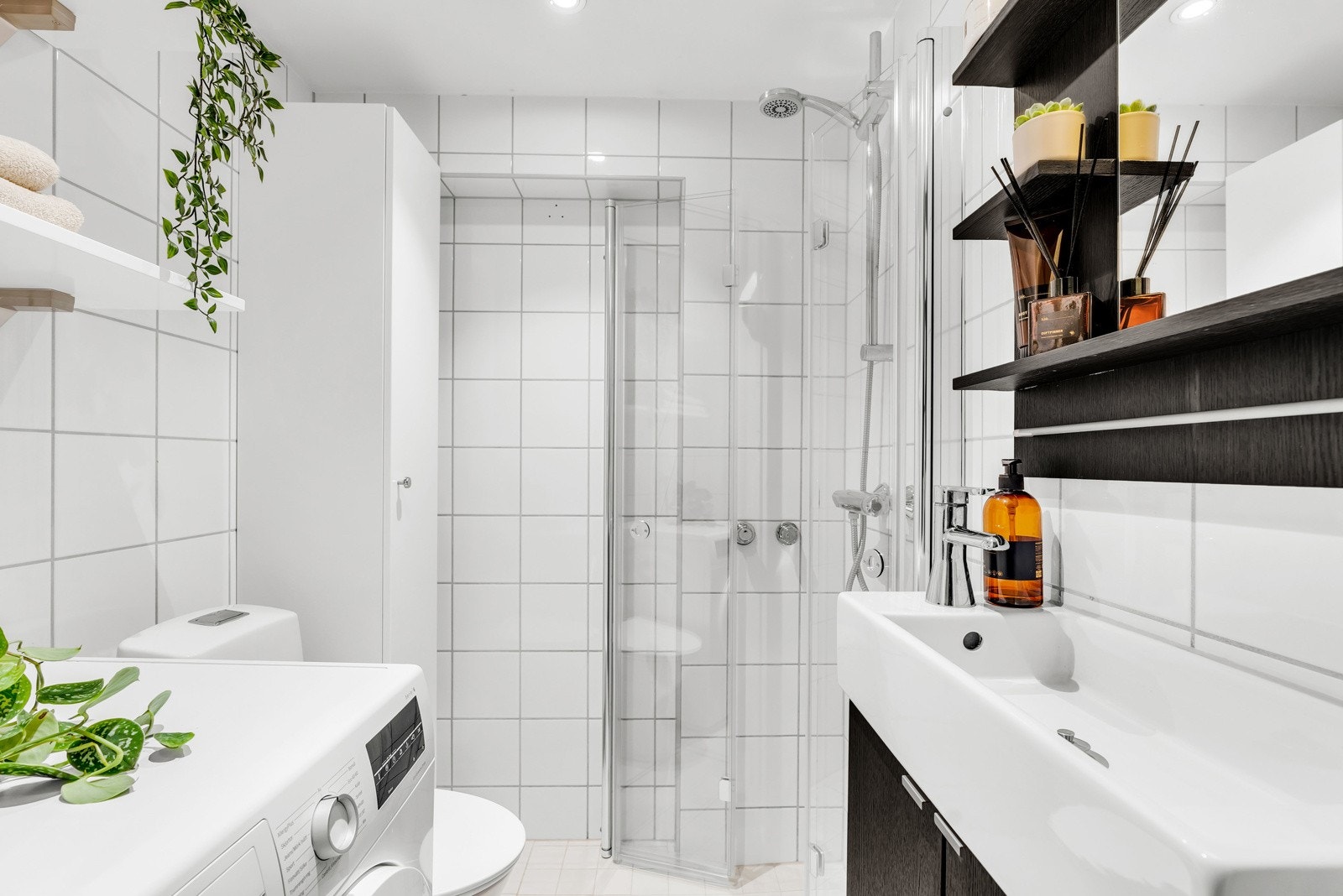 Badet er moderne og praktisk innredet med dusj, servant, speil og opplegg til vaskemaskin. Galleribilde