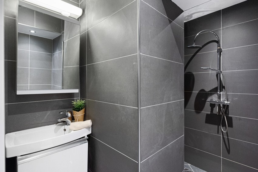 Badet inneholder toalett, dusjsone og vask med skapinnredning Galleribilde