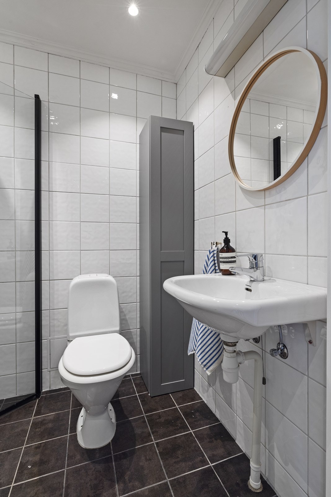 Badet består av vegghengt servant, speil over servant, overlys med stikkontakt, dusjhjørne med innfellbare glassdører, dusjarmatur tilkoblet regndusj og hånddusj, i tillegg til gulvstående toalett. Himling av malt flate med downlights Galleribilde