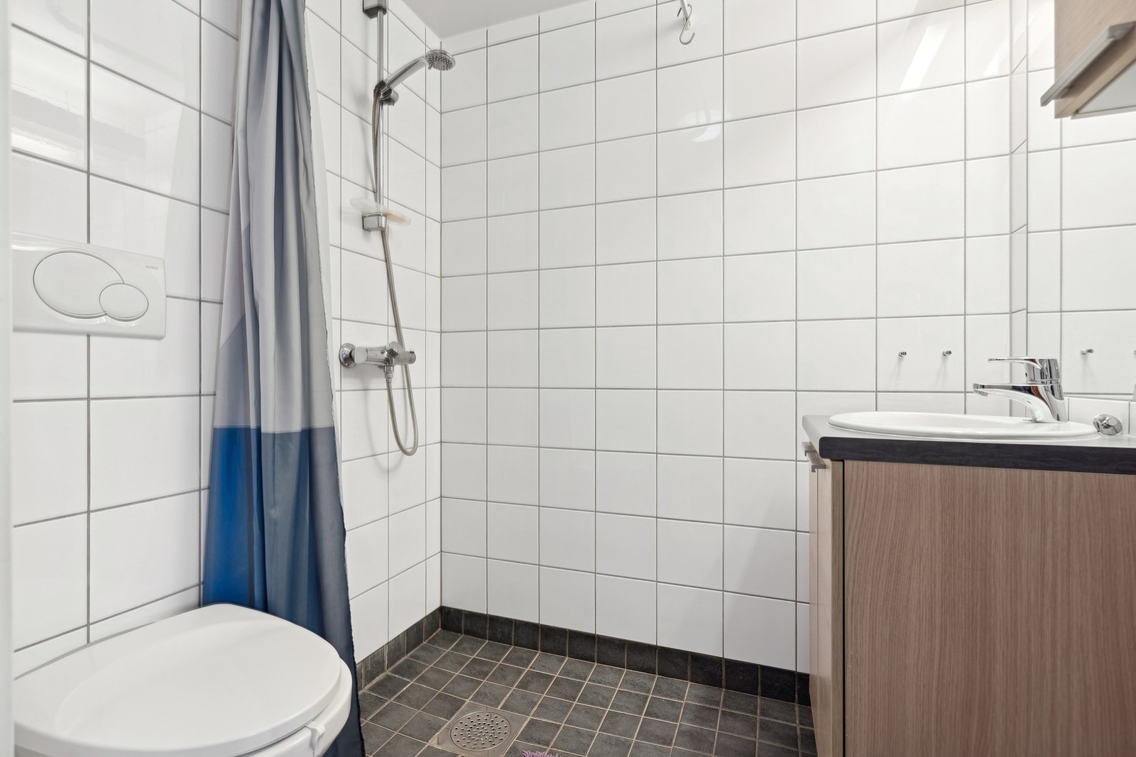 Et flislagt bad med elektriske varmekabler i gulv. Badet er innredet med servant på underskap, overskap og speil. Galleribilde