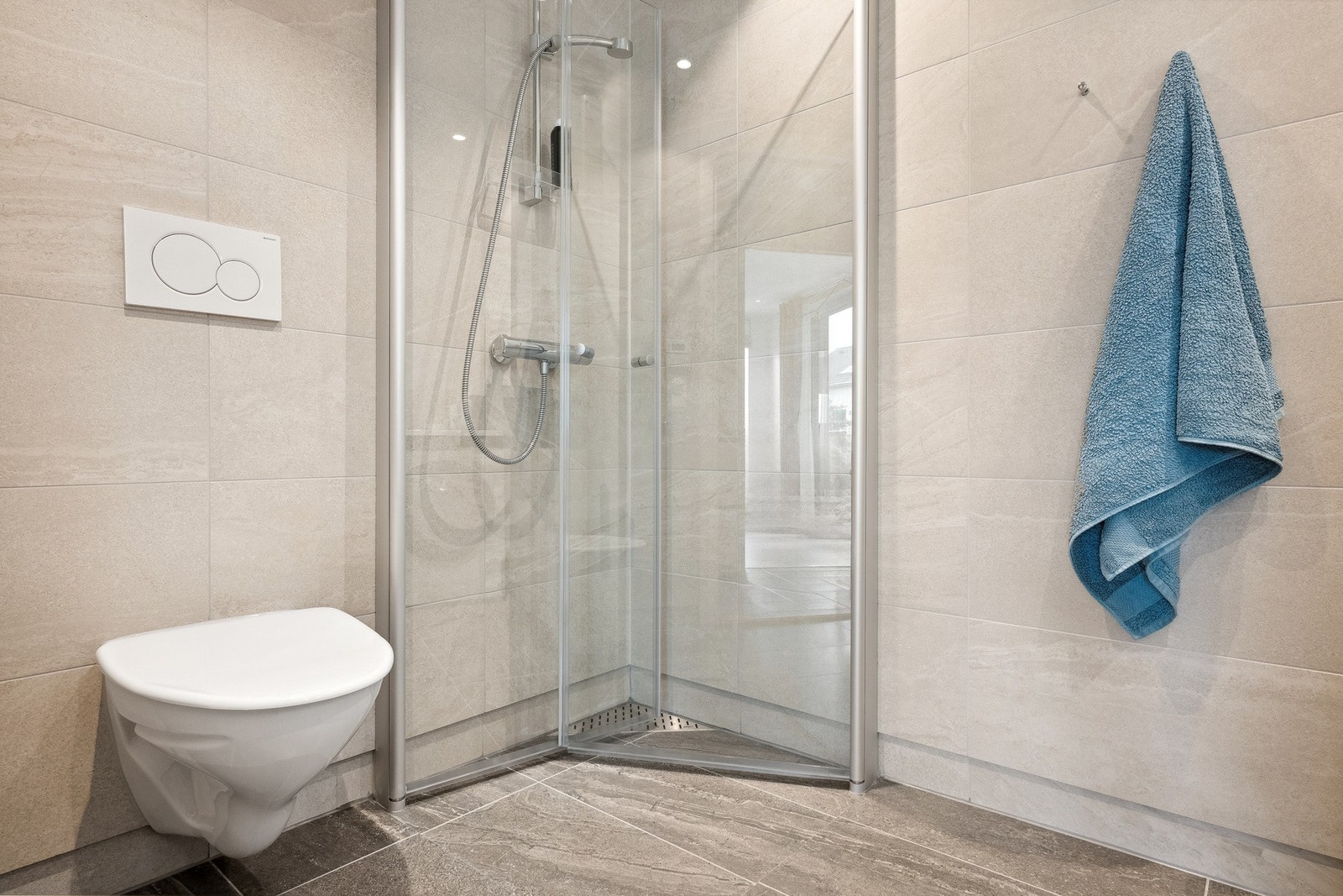 Lekkert helfliset bad av god størrelse med varme i gulv. Dusjhjørne med innfellbare vegger. Vegghengt toalett. Galleribilde