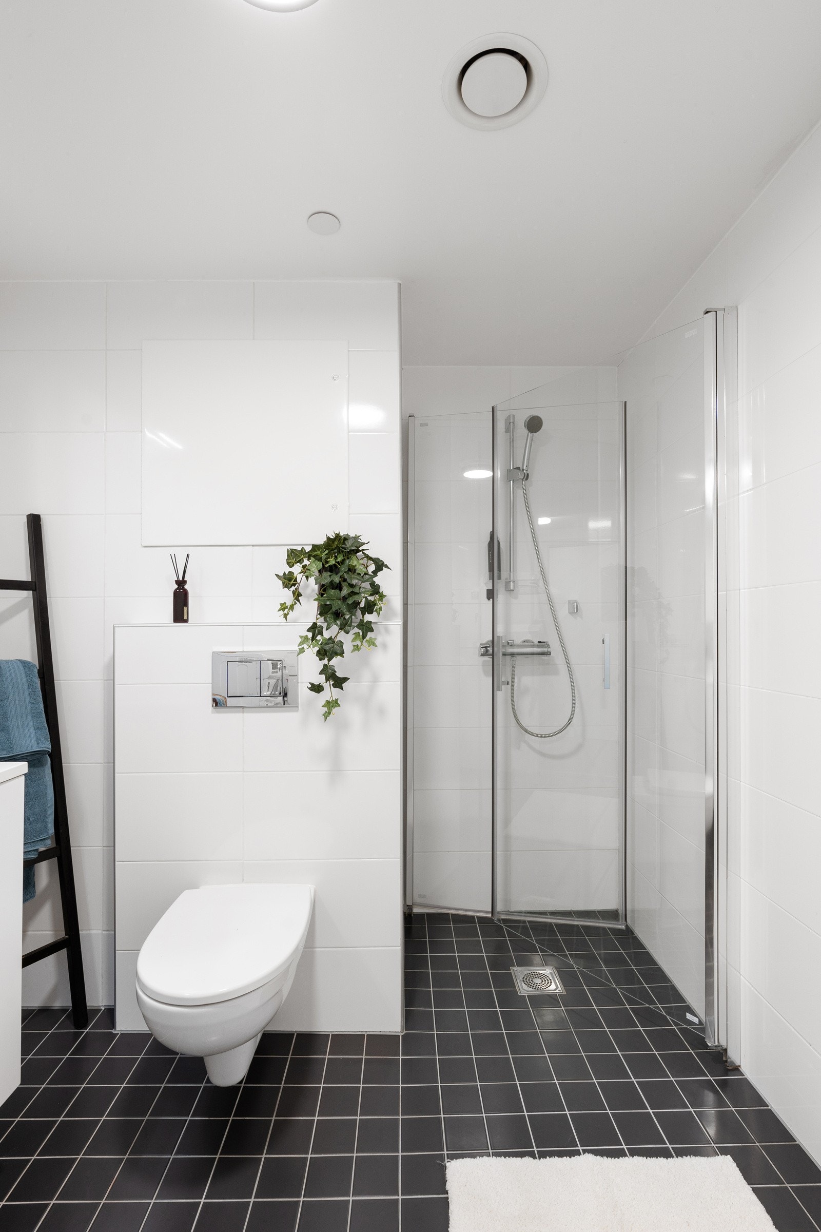 Flislagt bad som er utstyrt med romslig dusjhjørne, praktisk vegghengt wc og baderomsinnredning med oppbevaringsplass. Galleribilde