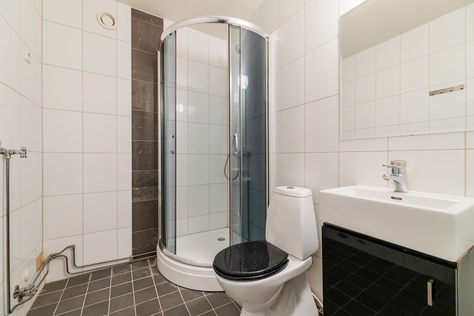 Flisbelagt bad med dusjkabinett og opplegg for vaskemaskin Galleribilde