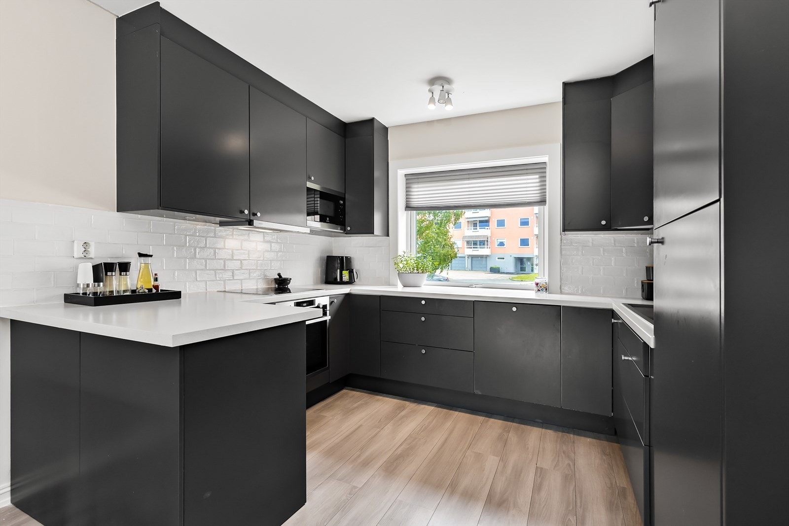 Lekkert kjøkken fra 2020 med sort innredning og hvit benkeplate og fliser som kontrast. Galleribilde