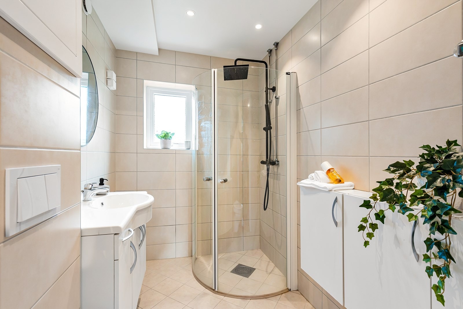 Rommet er innredet med vegghengt servantinnredning, vegghengt toalett, vegghengt skap og dusjhjørne med glassdører og vegghengt dusjarmatur med regndusj. Galleribilde