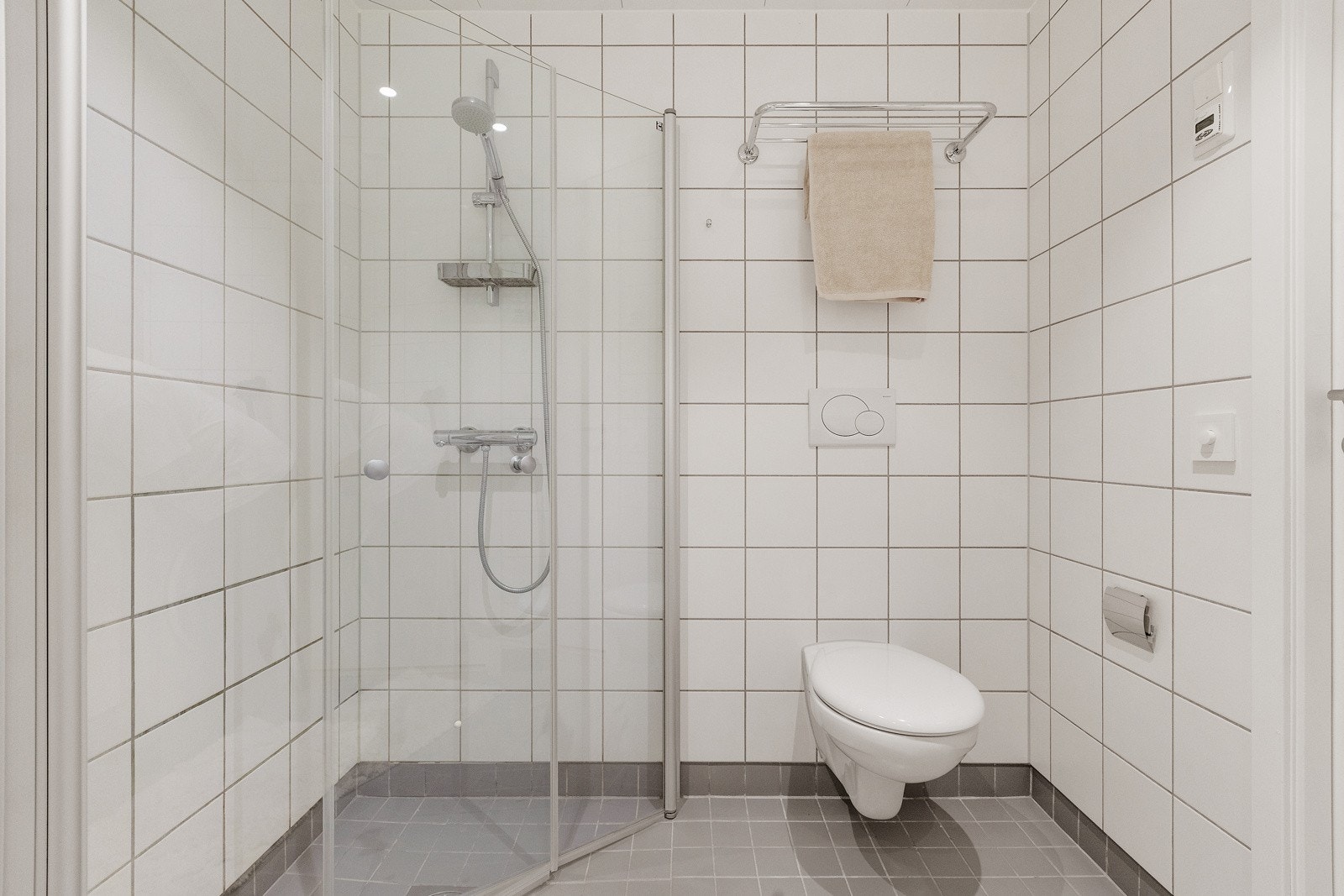 Eget dusjhjørne med svingbare glassdører og vegghengt toalett. Galleribilde
