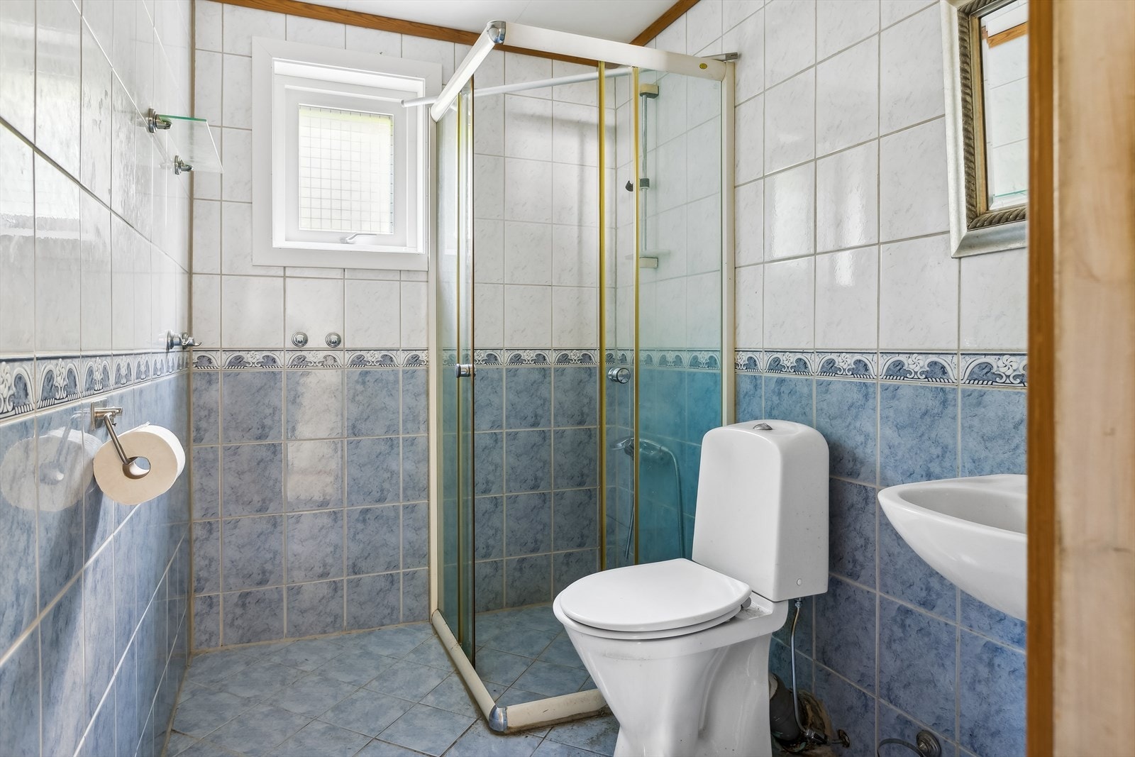 Helfliset bad innredet med dusjhjørne, gulvmontert toalett, vask med speil over. Rommet ventileres med mekanisk avtrekk. Galleribilde