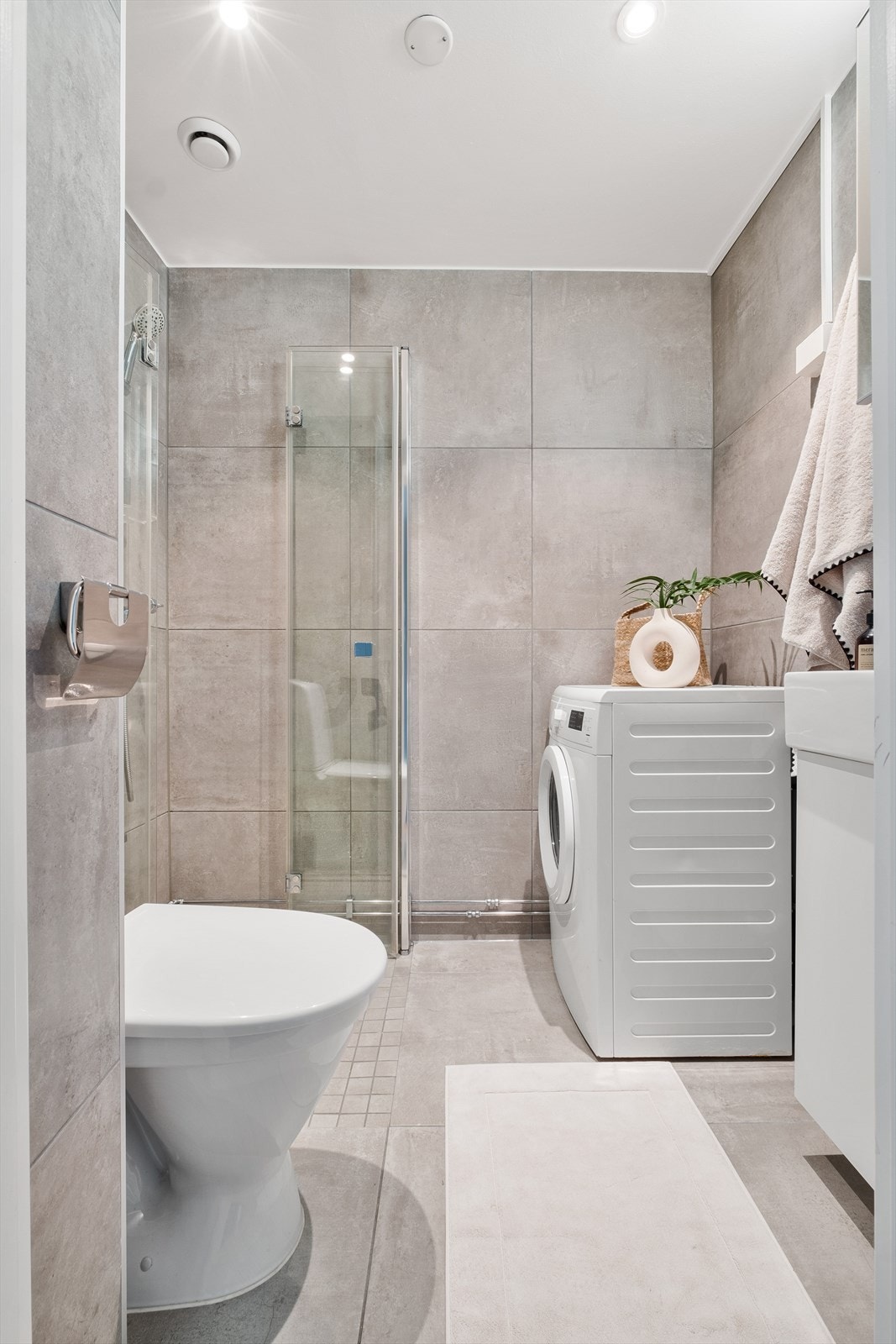 Pent flislagt bad oppusset i 2018 med moderne fliser, gulvstående wc, servantinnredning med underskap, dusj med foldbare dusjvegger. Opplegg for vaskemaskin. Downlights i tak. Varmekabler i gulv. Galleribilde