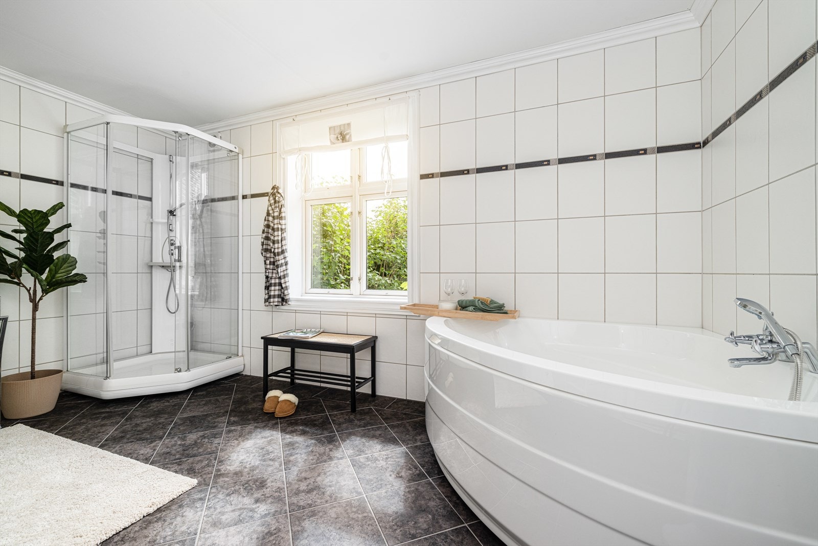 Badet er også innredet med dusjkabinett, et deilig hjørnebadekar og toalett. Galleribilde